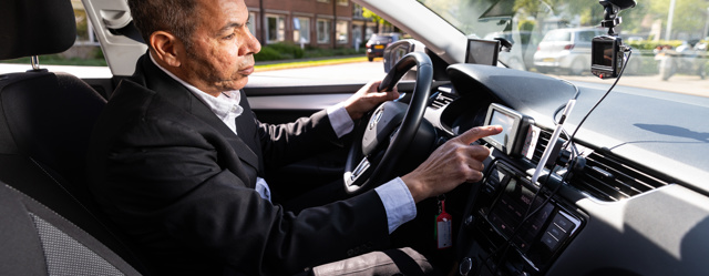 Een chauffeur zit achter het stuur en stelt de navigatie in.