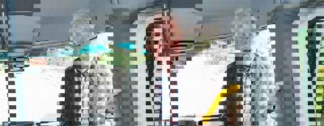 Man stapt de taxibus in terwijl hij zich vasthoudt aan de gele stang naast de deur.