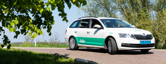 Een personenauto van Avan rijdt over de dijk op een zonnige dag.