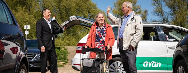 Man en vrouw lopen weg bij de Avan taxi, terwijl ze zwaaien naar de chauffeur.